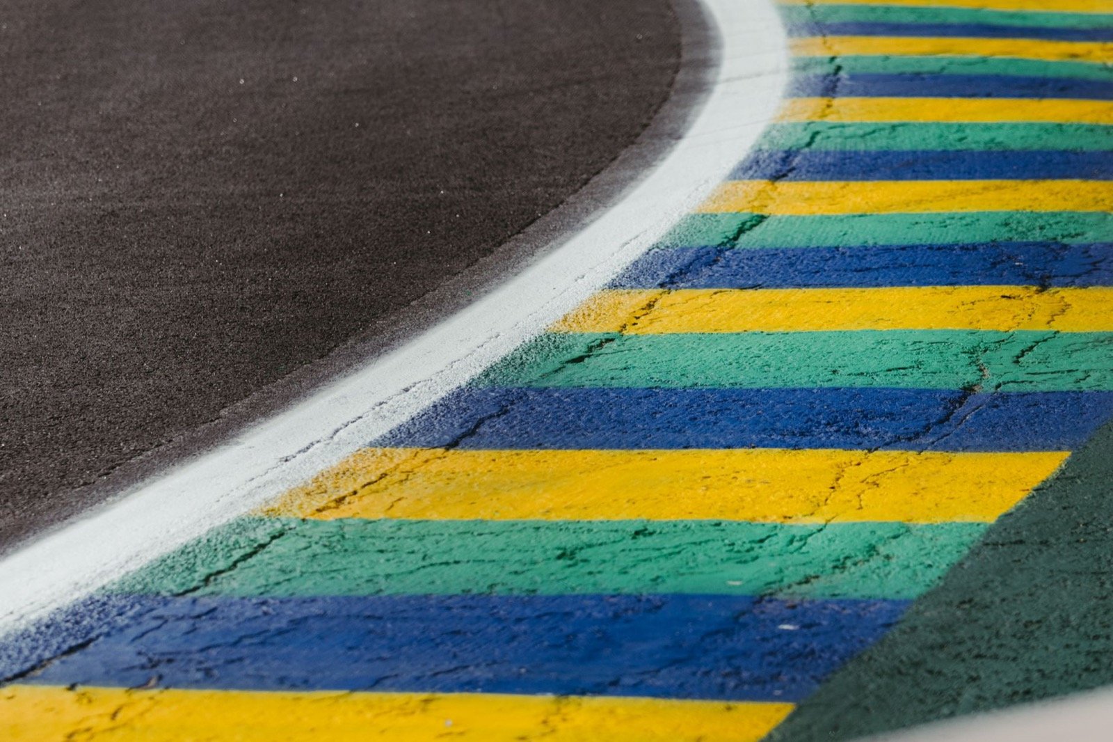 Zebra colorida e asfalto de autódromo brasileiro vistos de perto, na borda da pista